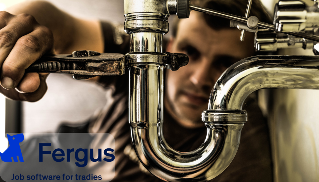 Plumber using a tablet to manage job profitability with Fergus software.